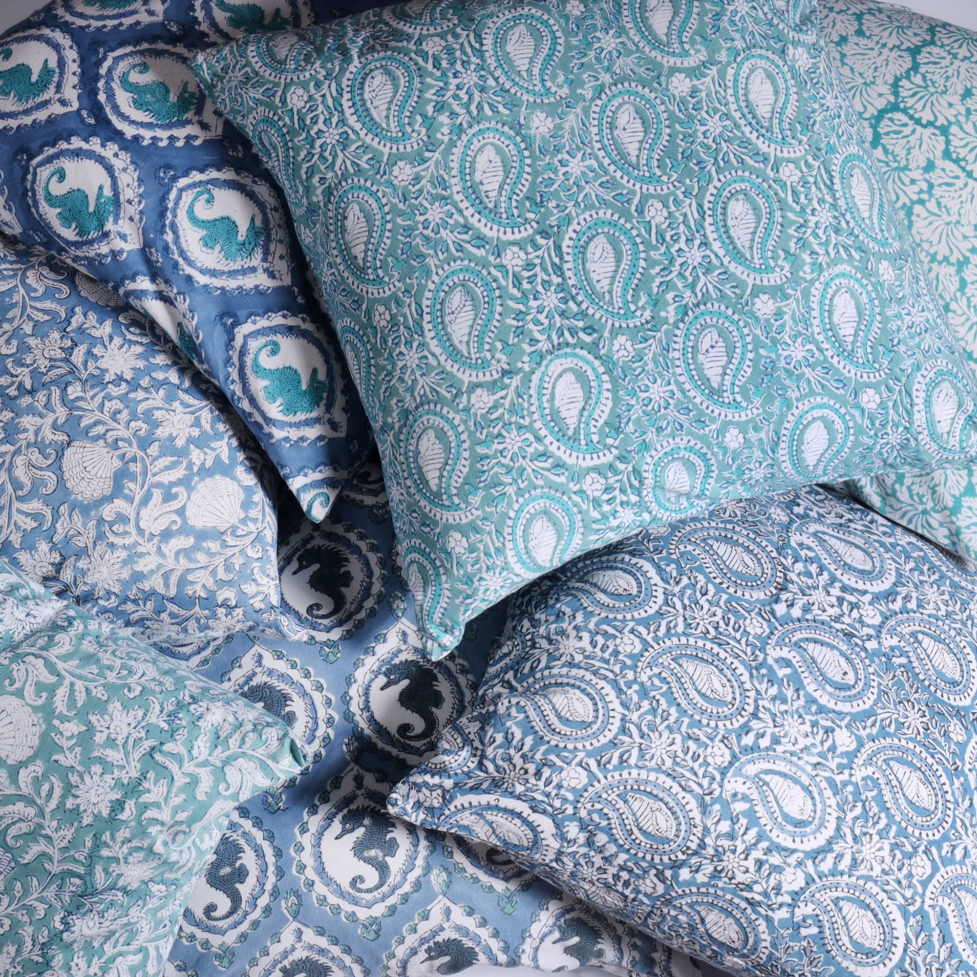 Azure Paisley Shell cushion which is Hand block printed fabric on a pile of other Hand block printed cushions