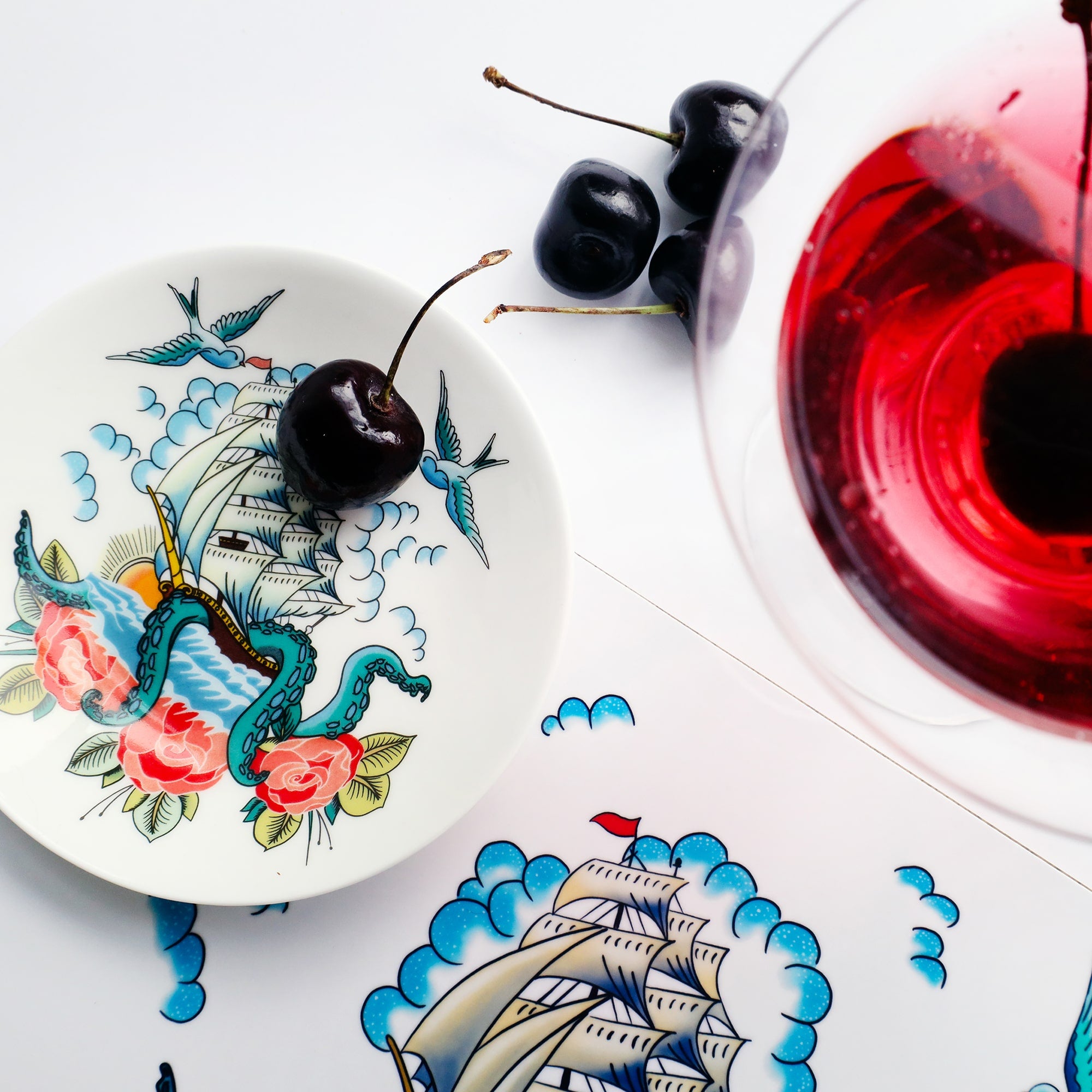 Nibbles dish with a ship and kraken design in the style of a tattoo, with a cherry in to show the scale.
