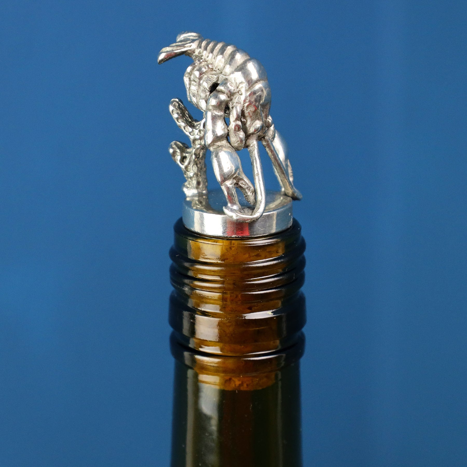 Pewter Lobster shaped Cork Stopper with body standing up placed in the top of a brown wine bottle