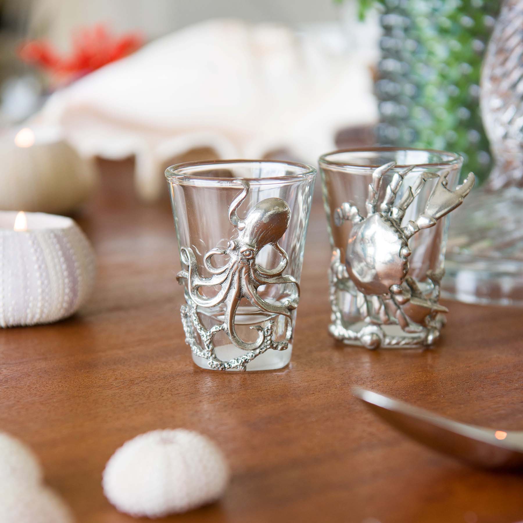 Close up of Pewter Crab  and Lobster Shot Glass on a table with shells in the foreground and jugs in the background
