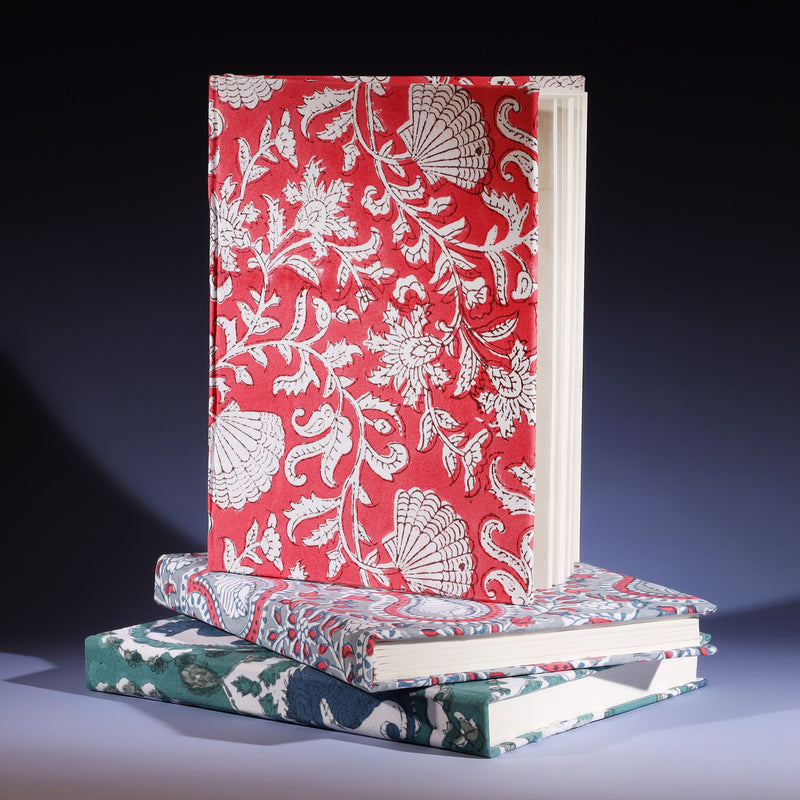 Hand Block printed hard backed notebook Seashell Flower in Campion on its side placed on a stack of other notebooks