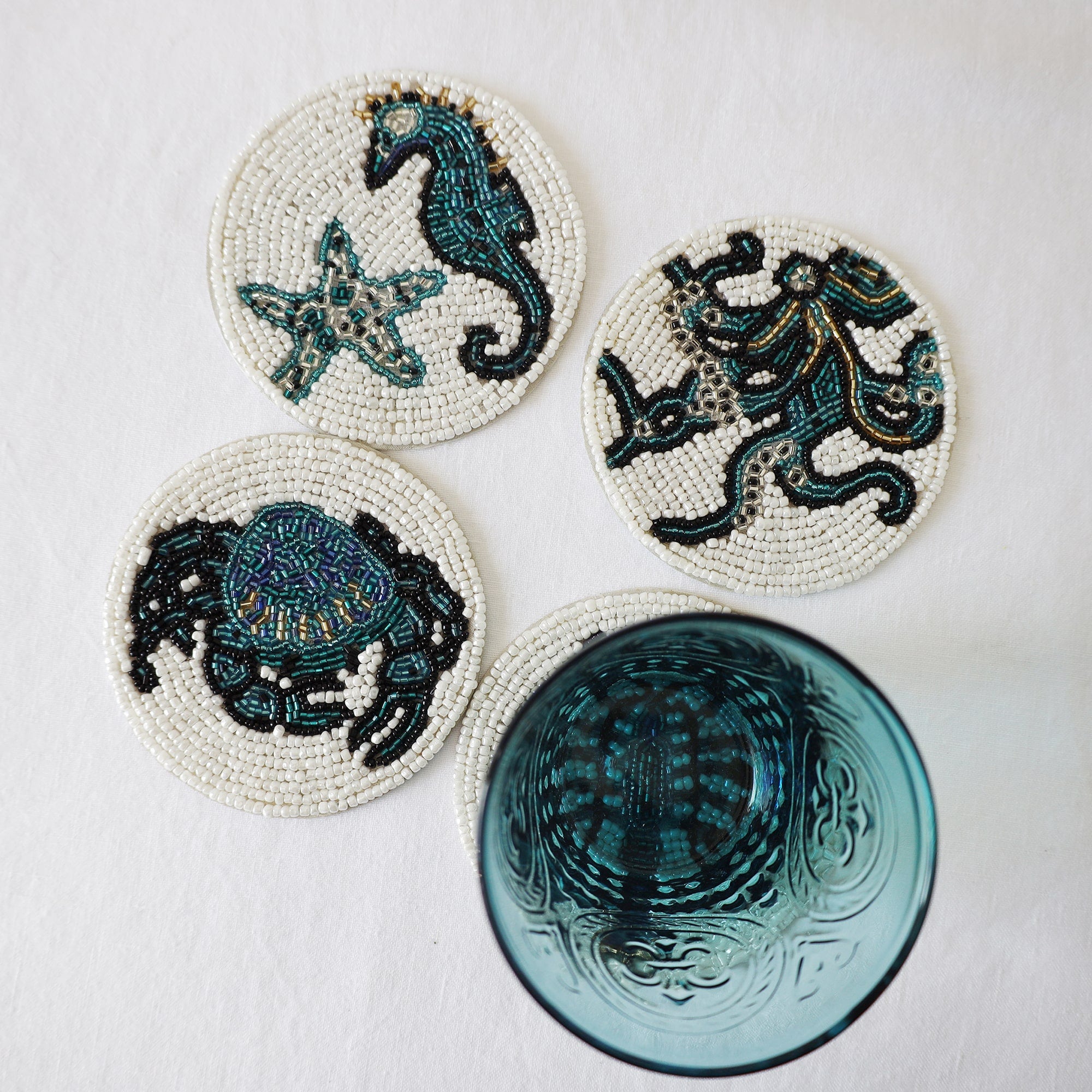 Handmade glass beaded coasters in Starfish and Shell,Octopus,Crab and Lobster,the Lobster is obscured by a glass.