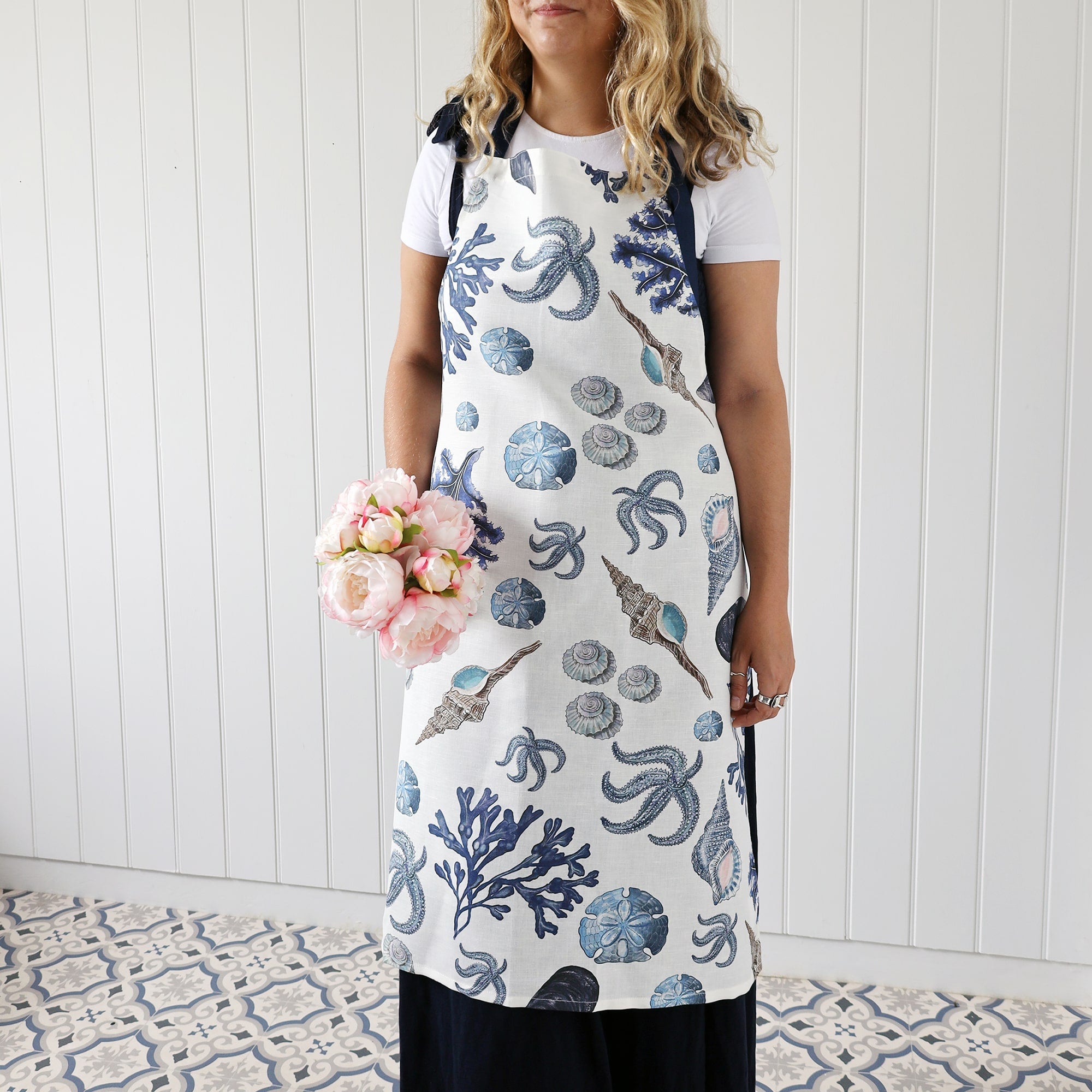 Our beachcomber apron being worn by a model who is also holding a small bouquet of flowers.