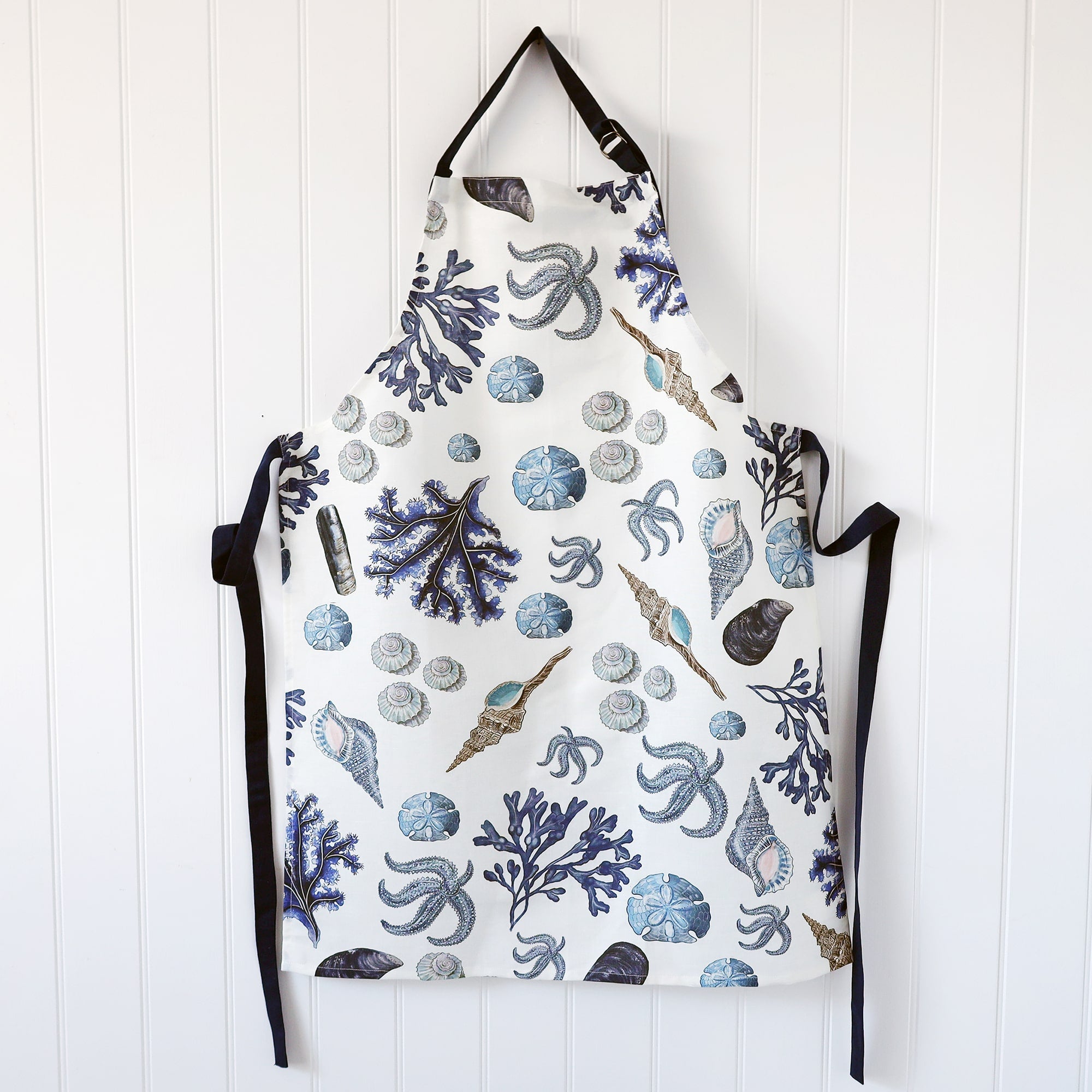 White Linen/Cotton mix apron with navy ties and  Navy strap around the neck,this can be adjusted to fit.On the print is our beachcomber design. 