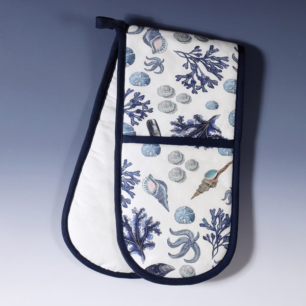 oven gloves with all over design of sea shells and seaweed in blues on white background with a navy trim