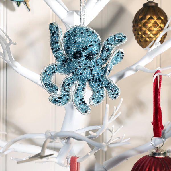 beaded blue and black octopus christmas decoration hanging on white branched christmas tree.