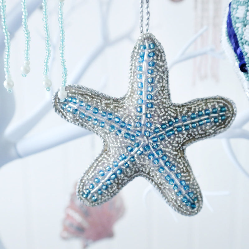 beaded silver and blue christmas decoration in the shape of starfish hanging from a tree