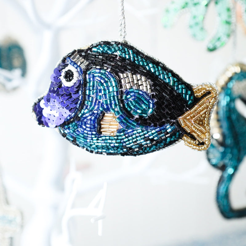 beaded christmas decoration in the shape of a fish with multi blue beads and gold fin and tail hanging from a tree