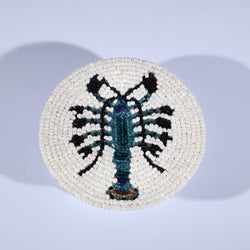 Handmade glass beaded coaster with a lobster design in Navy,Black and gold on white glass beads