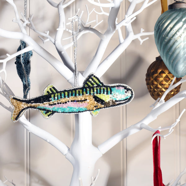 beaded mackerel  christmas decoration in bright turquoises, green and pink,hanging on white branched chritmas tree.