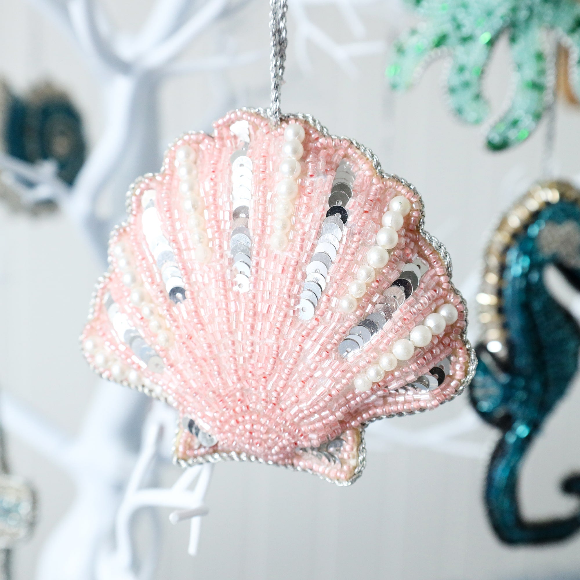 beaded pink scallop shell christmas decoration with silver sequins and white pearls you can see the seahorse decoration in the background