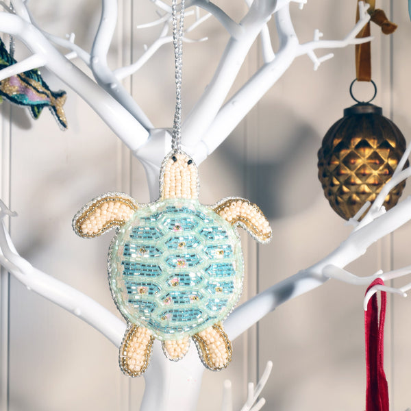 beaded hanging turtle christmas decoration hanging on white branched christmas tree.
