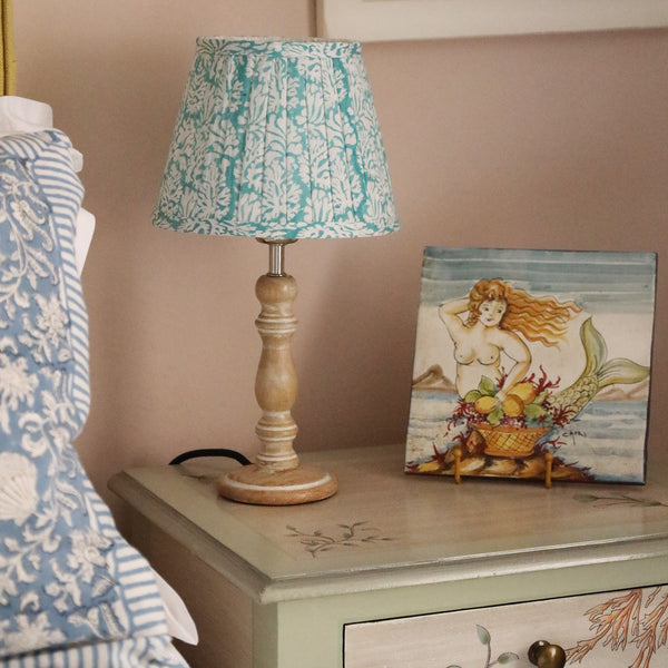 Small pleated Summer Skies Coraline pleated lampshade on a wooden base .The lampshade is on a hand painted bedside cabinet,also on the cabinet is a painting of a mermaid