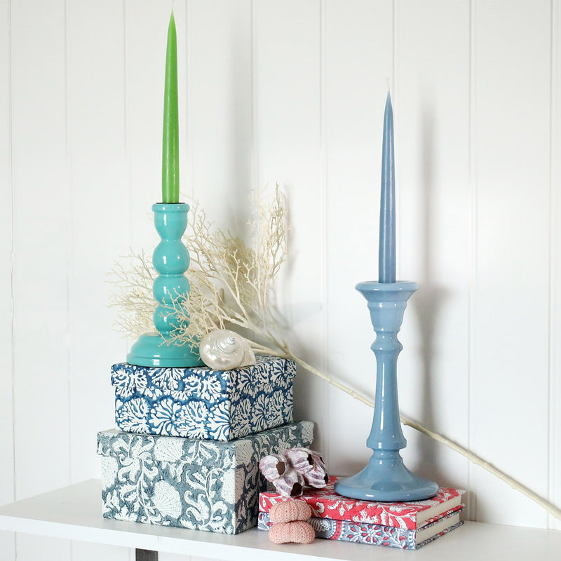 Powder Blue Tidal candle holder placed on a couple of notebooks.Next to this is another candle holder placed on a couple of hand blocked painted boxes.Both have candles in them,there are shells also in the picture