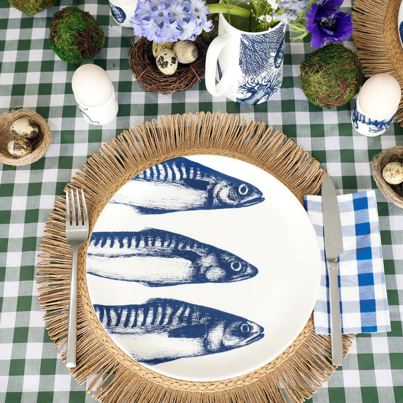Bone China White  plate with hand drawn illustration our classic 3 mackerel in Navy on a raffia placemat. The table has been set for Easter with moss balls and eggs in a nest and egg cups.