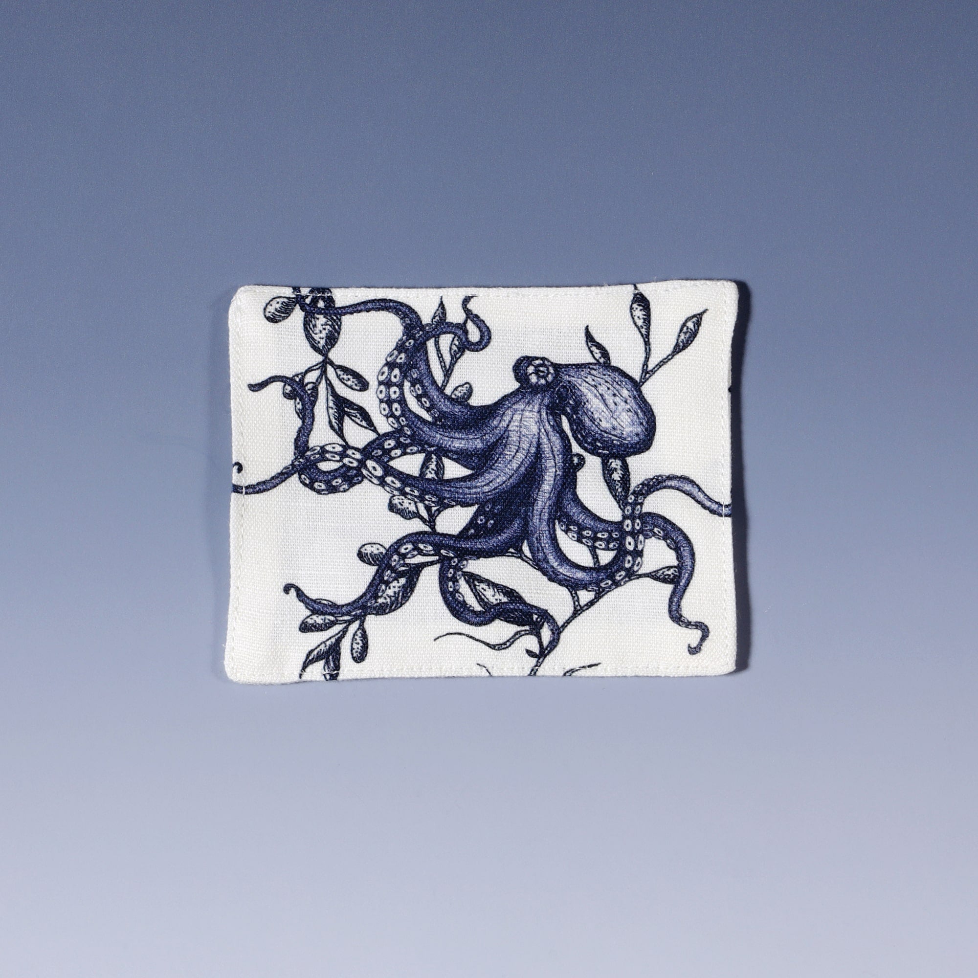 Cotton and linen mix white fabric rectangular coaster.Design on both sides is a hand drawn illustration of an octopus  in seaweed in navy blue.Set of four