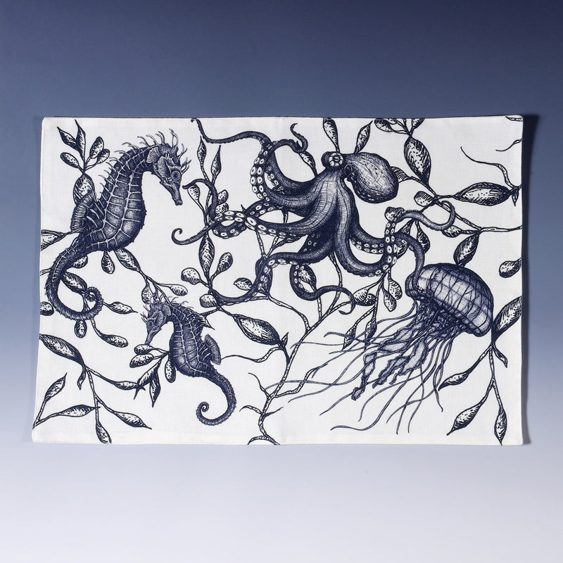 Cotton and linen mix white fabric rectangular placemat.Design on both sides are hand drawn illustrations of navy octopus,jellyfish and a couple of seahorses swimming around in seaweed.Set of four