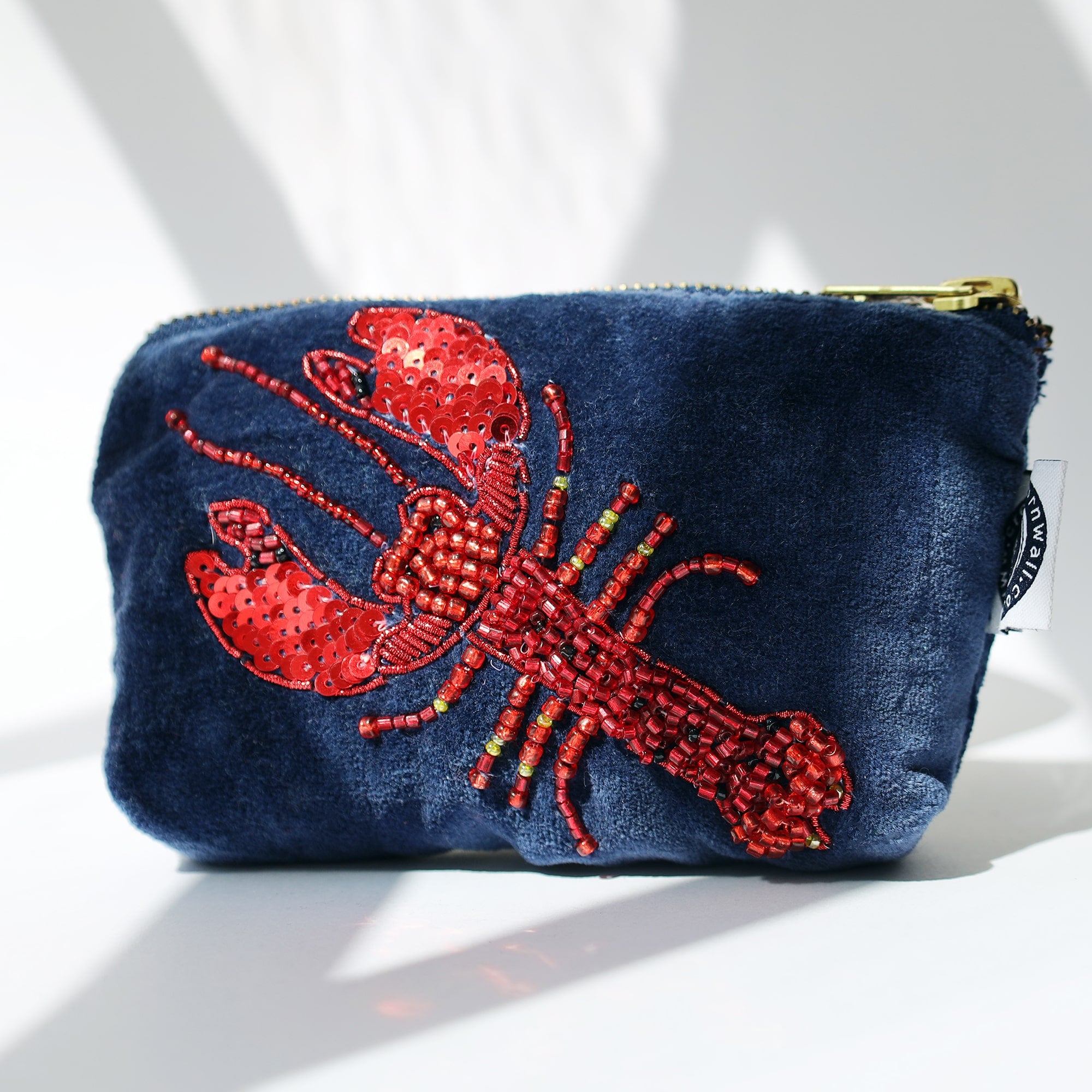 Velvet coin purse adorned with a vibrant red lobster embroidered in beads and sequins, standing out against a deep navy blue background, featuring intricate detailing and a gold zipper.