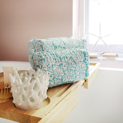 Tubular shaped cosmetic bags with Summer Skies Coraline design,medium and small placed on a shelf placed over the bath.on the shelf is a body brush and coral candle holder.Behind is the window ledge and a starfish leaning against it