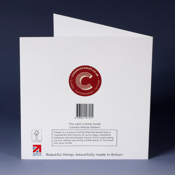 back of white greeting card with barcode, description and red cream corwnall logo standing on an ombre blue paper background