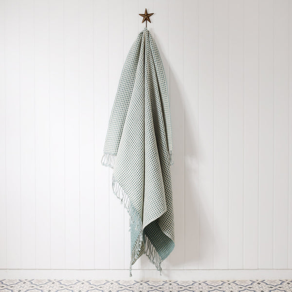 cream & duck egg honeycomb throw hanging on a starfish brass hook on a white tongue & groove wall