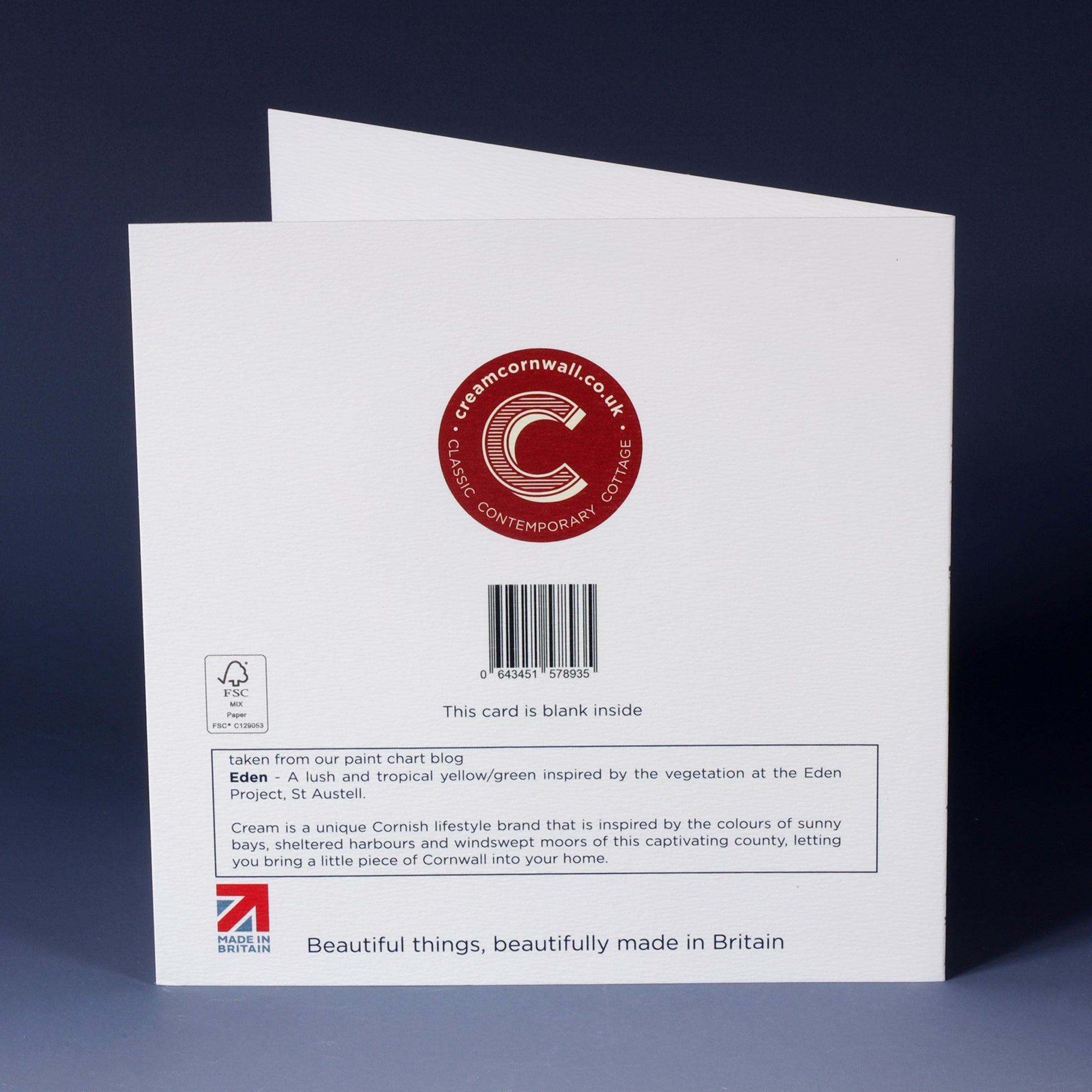 back of white greeting card with barcode, description and red cream cornwall logo standing on an ombre blue background