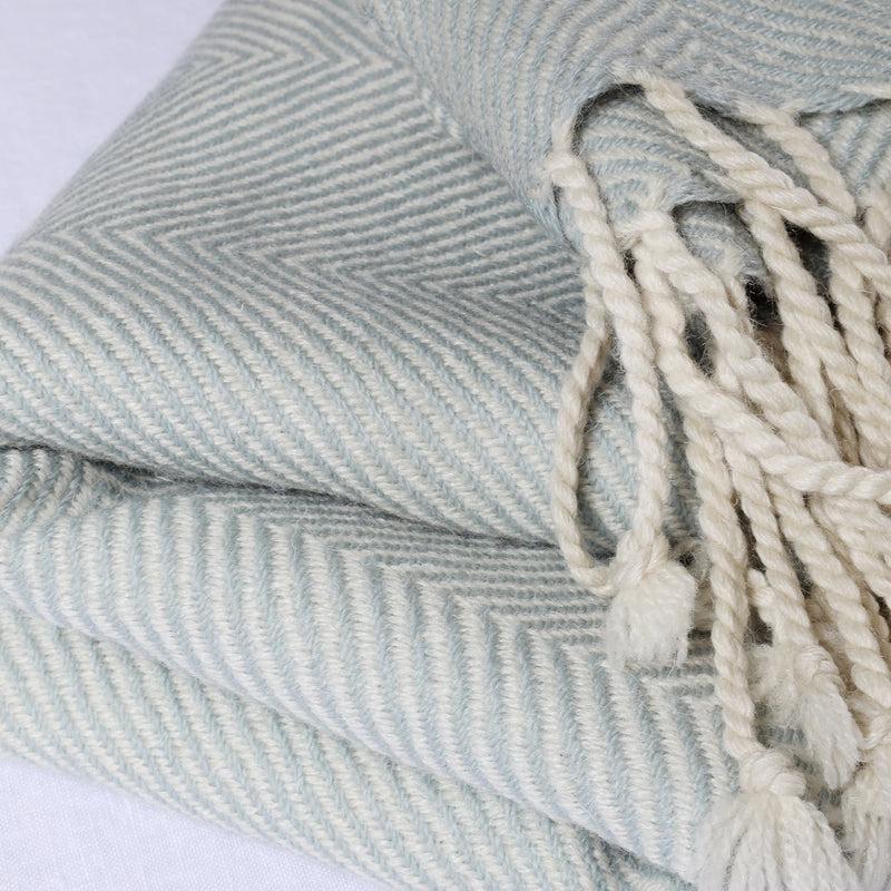 folded light grey and cream herringbone throw on a white background showing the weave detail and the knotted tassel fringe