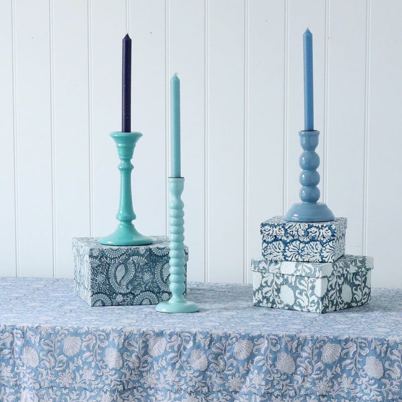 Seashell Blue Drift Candle holder placed on one of our Samudra linen collection table cloths.Also on the table are other candle holders placed on our hand painted boxes,each have matching candles