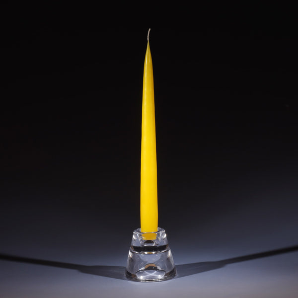 lemon coloured tapered dinner candle in a small glass candle holder on an ombre blue background