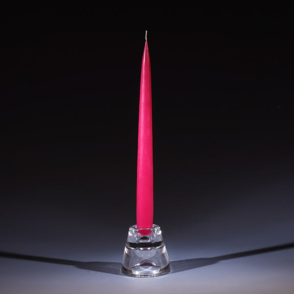 light cherry coloured tapered dinner candle in a small glass candle holder on an ombre blue background