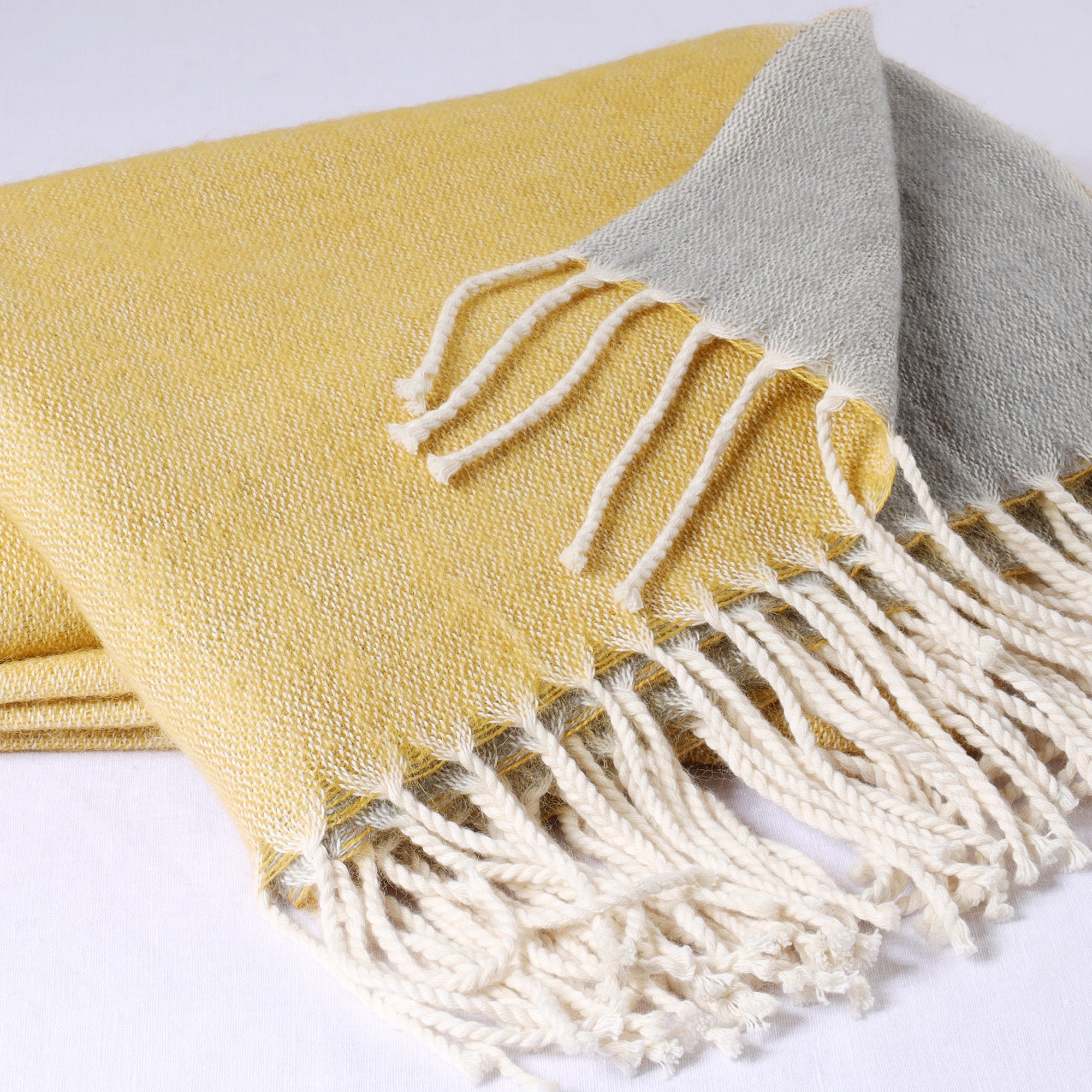 folded brushed reversible mustard and grey throw on white background showing the weave and twisted fringe detail