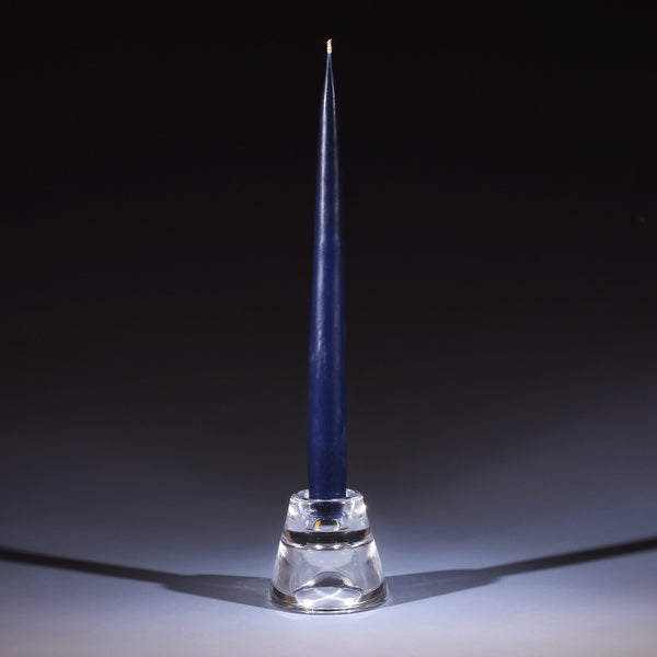 navy blue tapered dinner candle in a small glass candle holder on an ombre blue background
