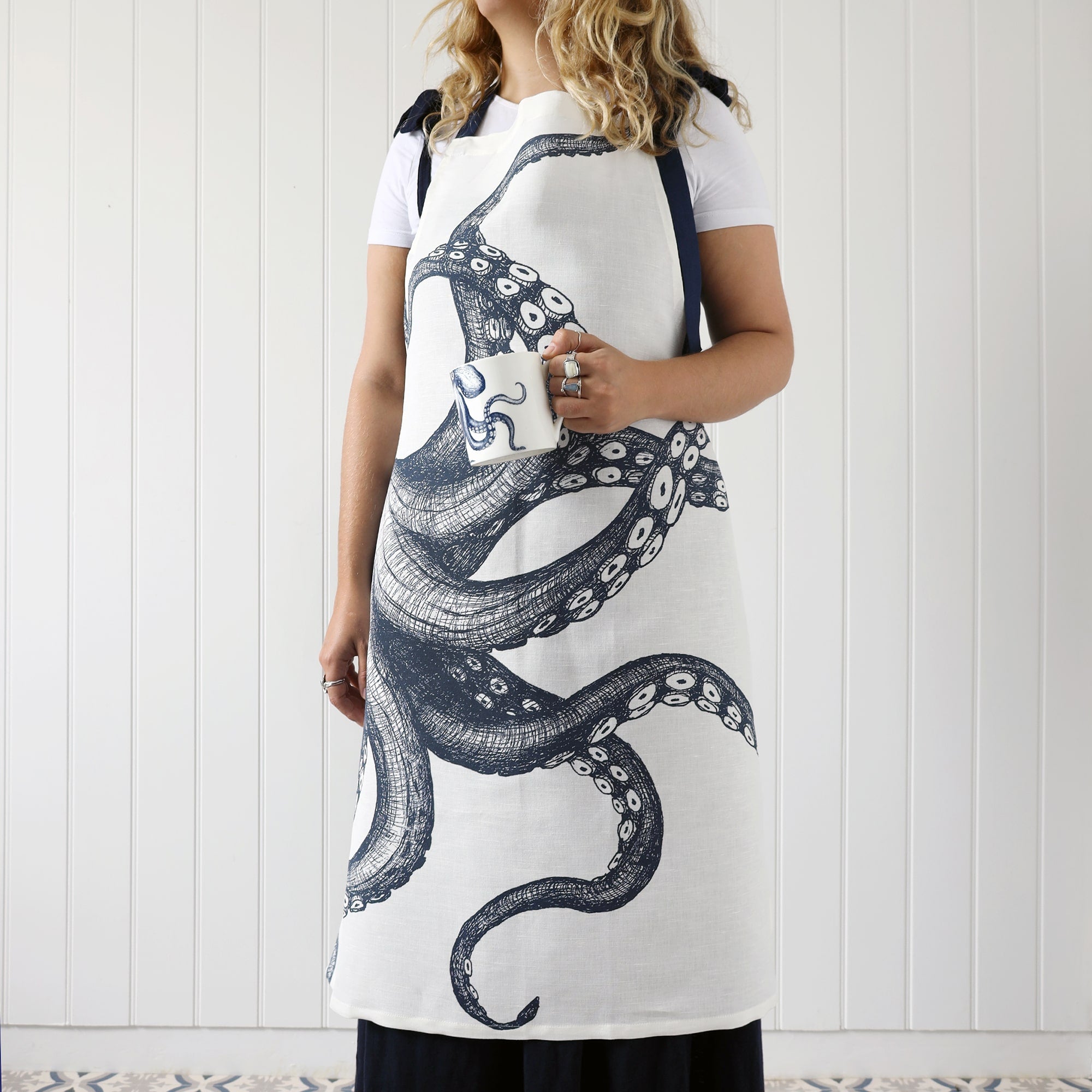 Our octopus apron being worn by a model who is also holding an octopus mug