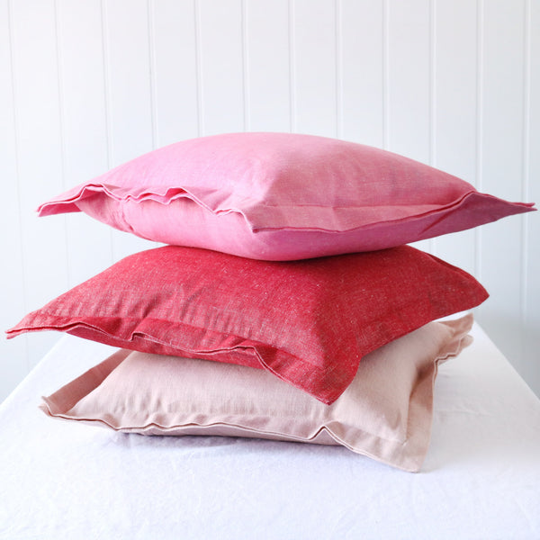 soft pink, red and hot pink chambray cushions with double flange in a row on white background
