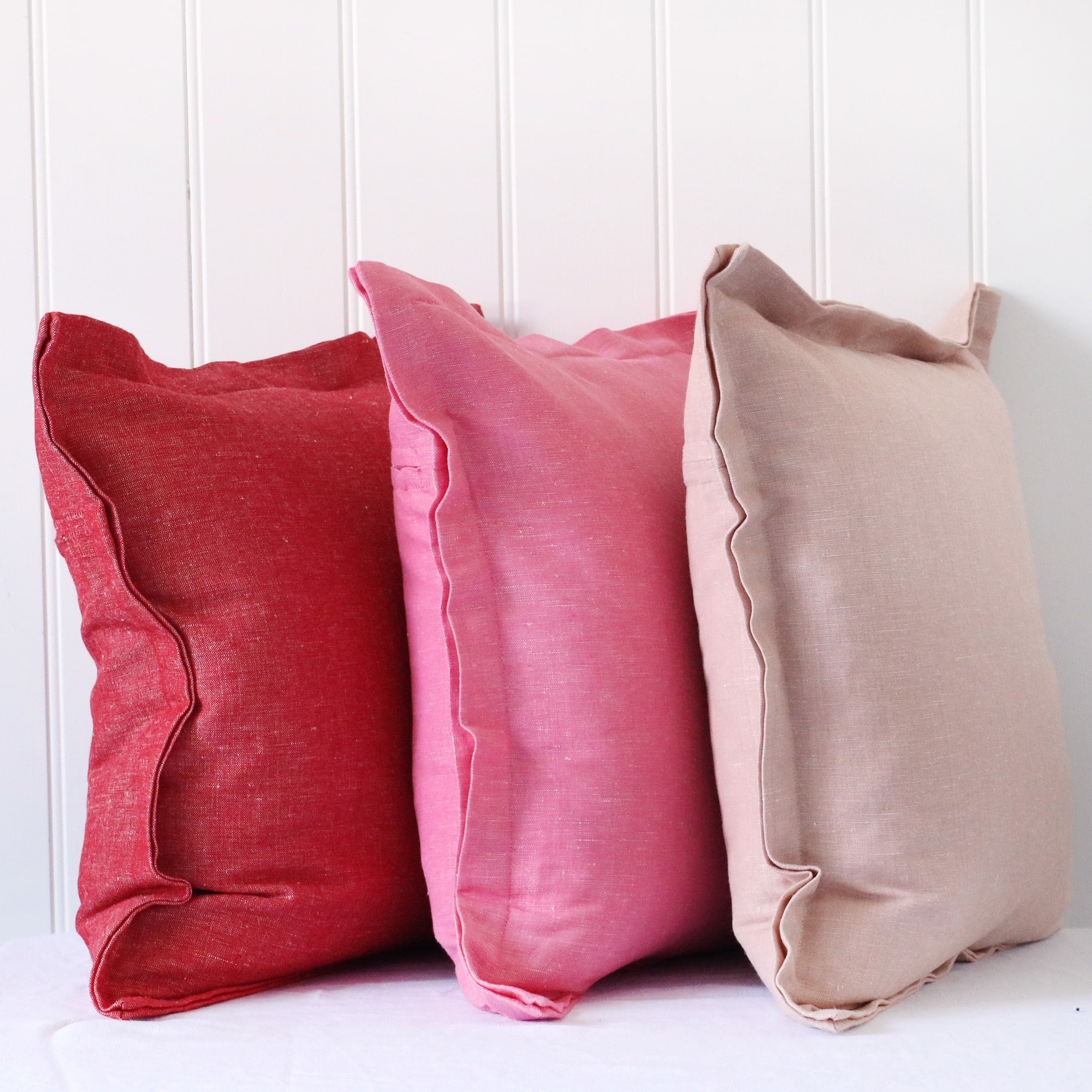 red, hot pink and soft pink chambray cushions with double flange in a pile on white background