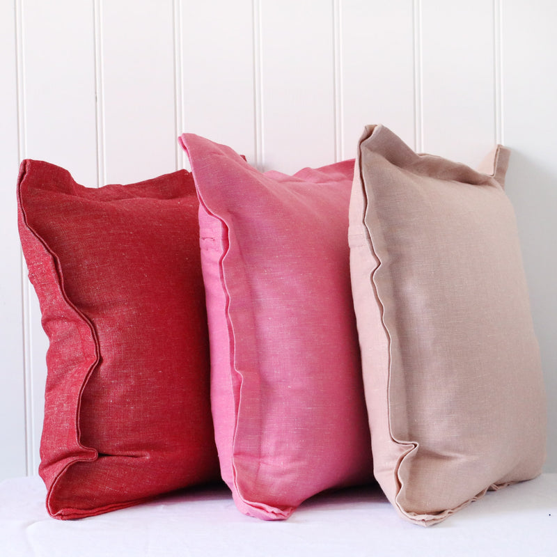 red, hot pink and soft pink chambray cushions with double flange in a row on white background