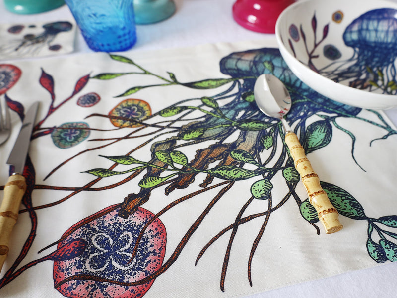 Close up of Reef design showing a Jellyfish placed next to a matching placemat on a tablecloth with Bamboo cutlery
