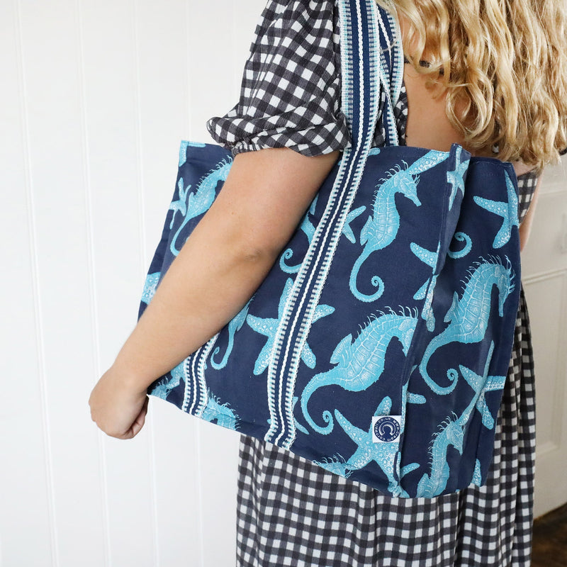 Seahorse and Starfish decorated Tote bag in a cotton and linen mix with large braided handles being worn over the shoulder by a model.