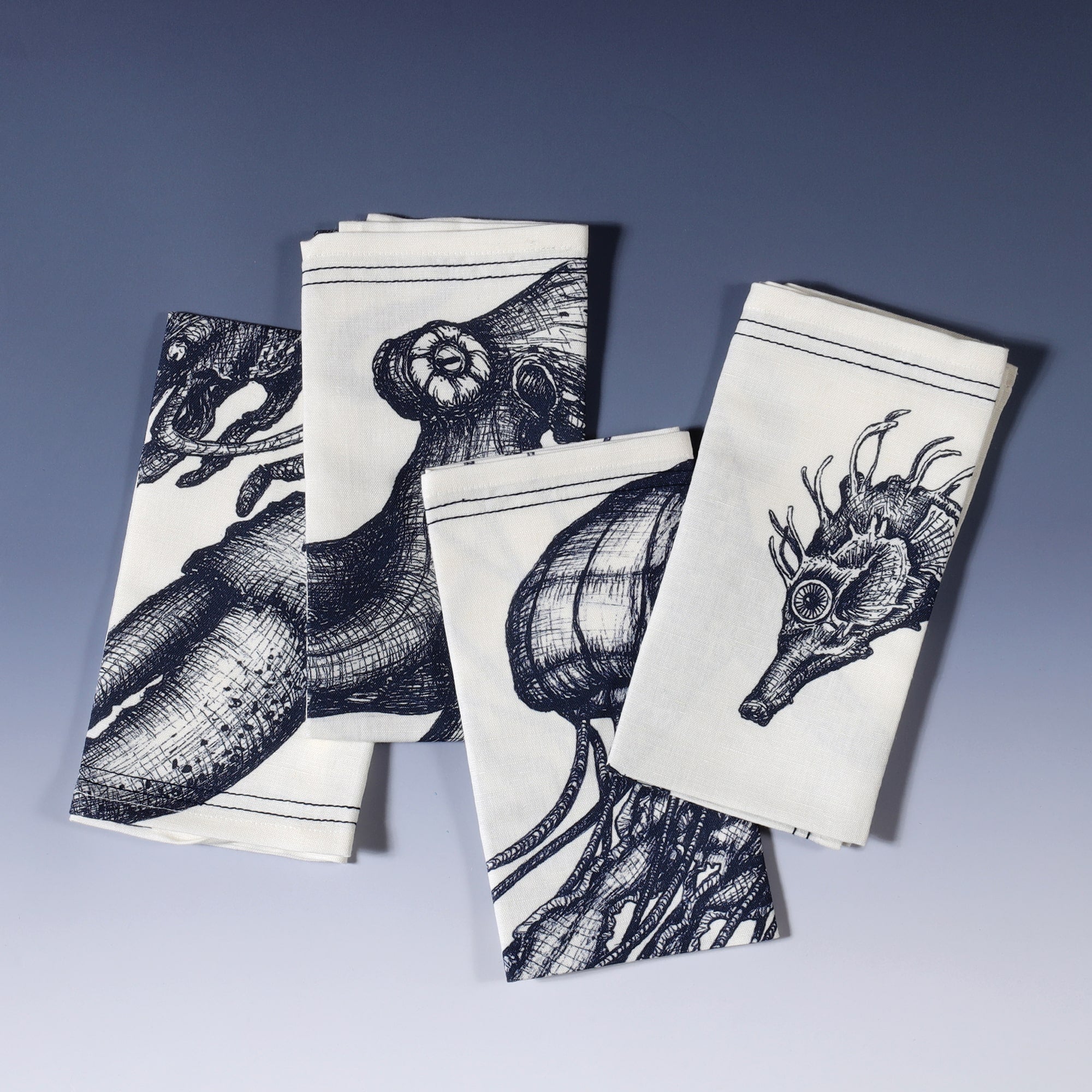 Blue & white linen napkins with seahorse, lobster, octopus and jellyfish hand drawn illustrations,set of four folded on top of each other