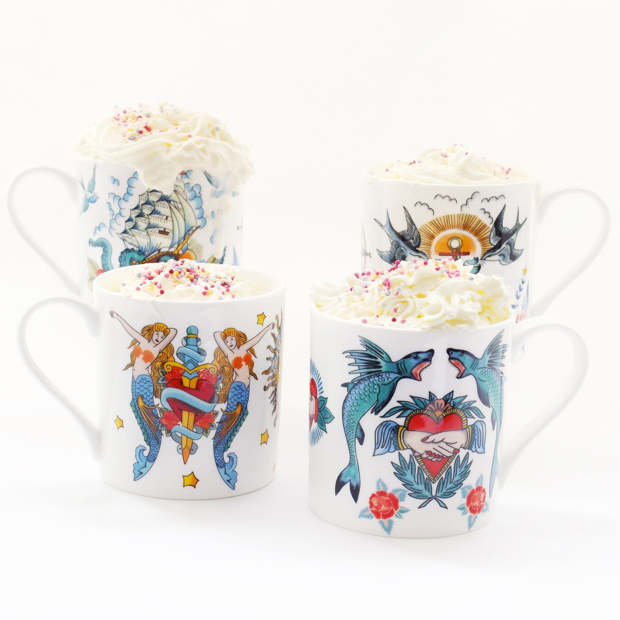 4 white mugs decorated in brightly coloured sailors tattoo's inspired designs. Each is filled with whipped cream and has hundreds and thousands sprinkled on the top.