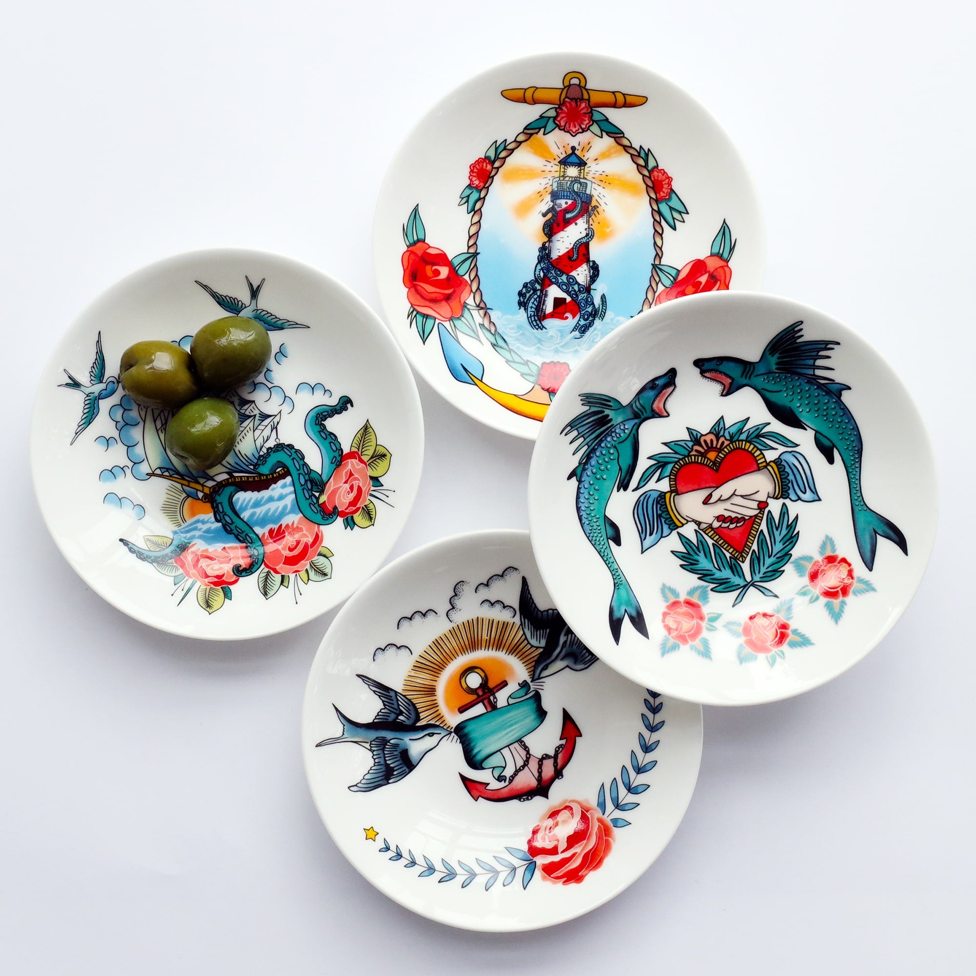 4 nibbles dishes with brightly coloured sailors inspired tattoo designs. One of the dishes has 3 green olives in to show the scale of the dish.