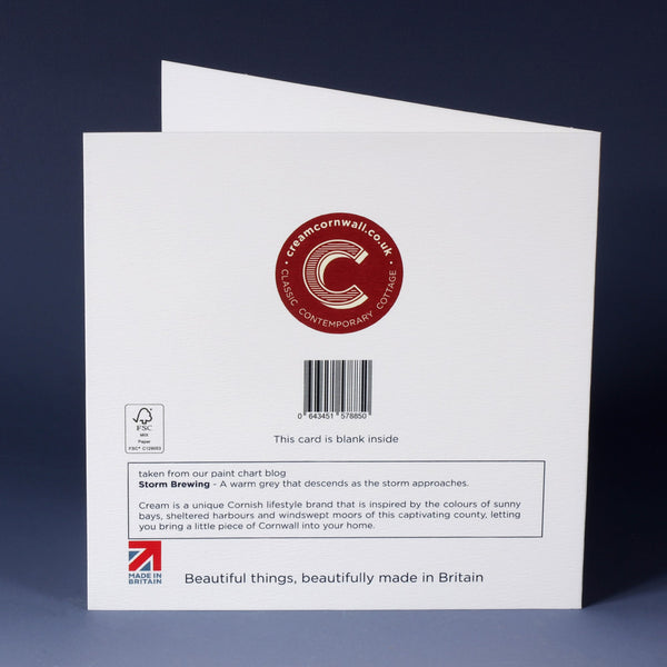 back of white greeting card with barcode, description and red cream cornwall logo standing on an ombre blue background