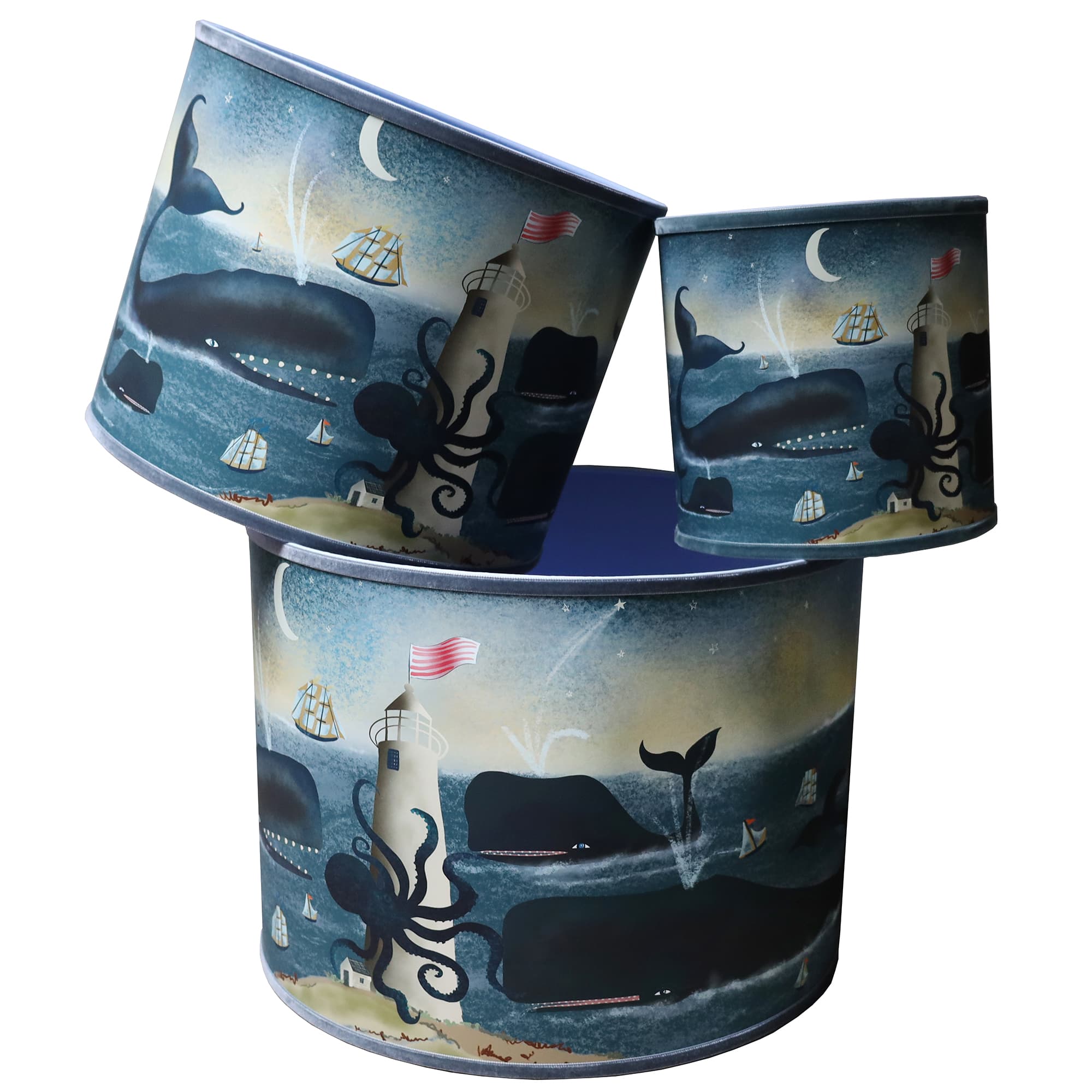 Three drum-shaped lampshades featuring a whimsical ocean scene with large, playful whales swimming around a lighthouse. The design includes an octopus wrapping around the base of the lighthouse, small sailboats drifting on the water, and a crescent moon in a starry sky. The whales spout water, adding movement to the serene night seascape. The artwork is vibrant and imaginative, capturing the charm of marine life and nautical folklore. The lampshades vary in size and stack together, showcasing the same encha