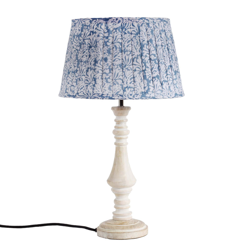 Medium Coastal Blue pleated lampshade in hand blocked print in blue and white,fabric finished edges and lined in white on a wooden lampbase