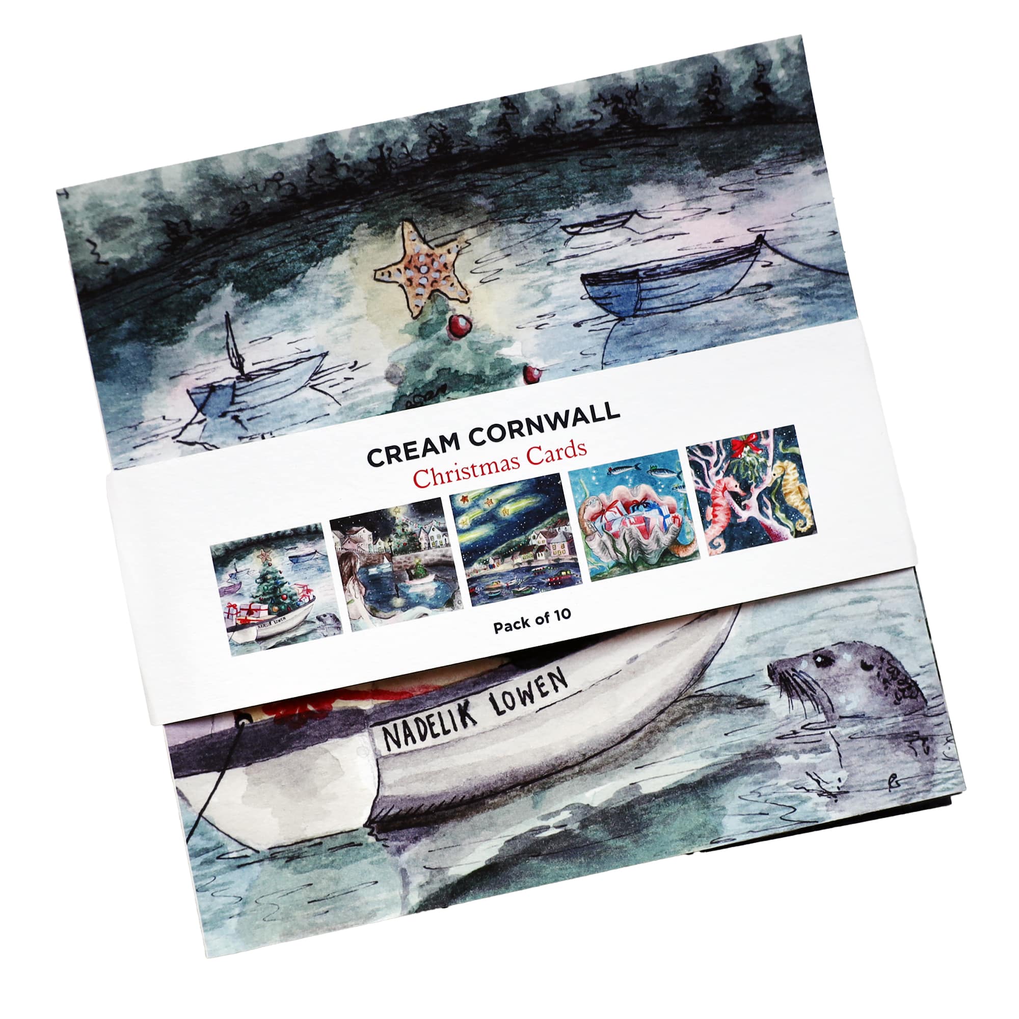 A pack of 10 Cream Cornwall Christmas cards featuring a watercolor-style illustration of boats on a calm lake with a Christmas tree and starfish in the background. The front card shows a boat with 'Nadelik Lowen' (Cornish for Merry Christmas) written on it, and a curious seal peeking out of the water. The packaging displays small thumbnails of additional festive card designs