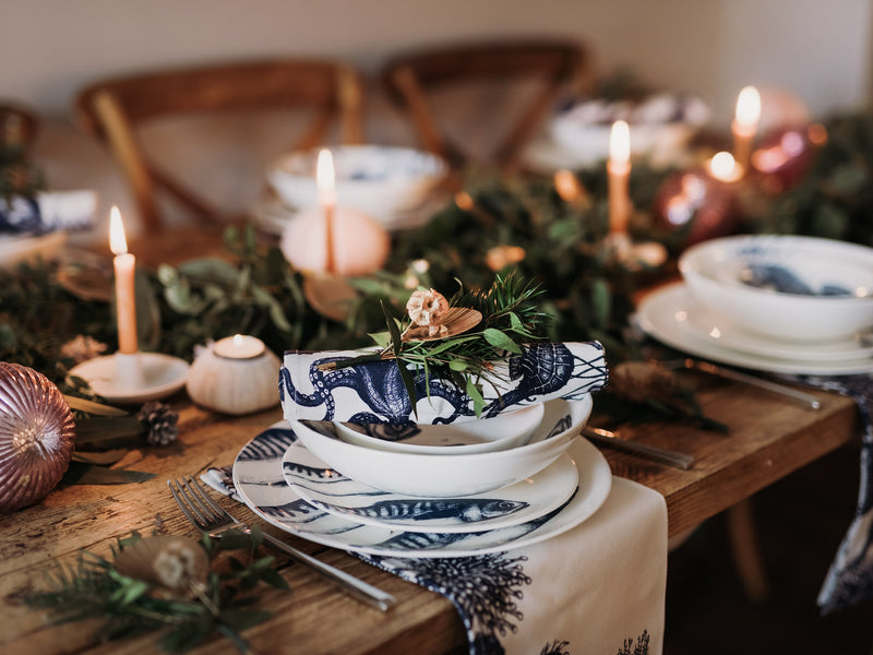 Pasta bowl in Bone China in our Classic range in Navy and white in the Mackerel design,placed on a matching dinner plate and has a smaller bowl placed inside.All are on a table setting and the table is decorated with foliage and candle holders