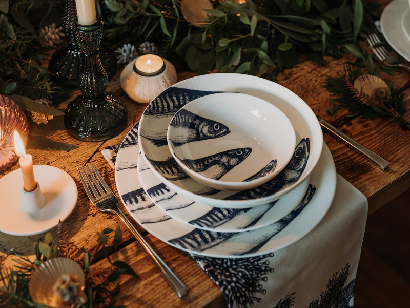 Pasta bowl in Bone China in our Classic range in Navy and white in the Mackerel design,placed on a matching dinner plate and has a smaller bowl placed inside.All are on a table setting and the table is decorated with foliage and candle holders