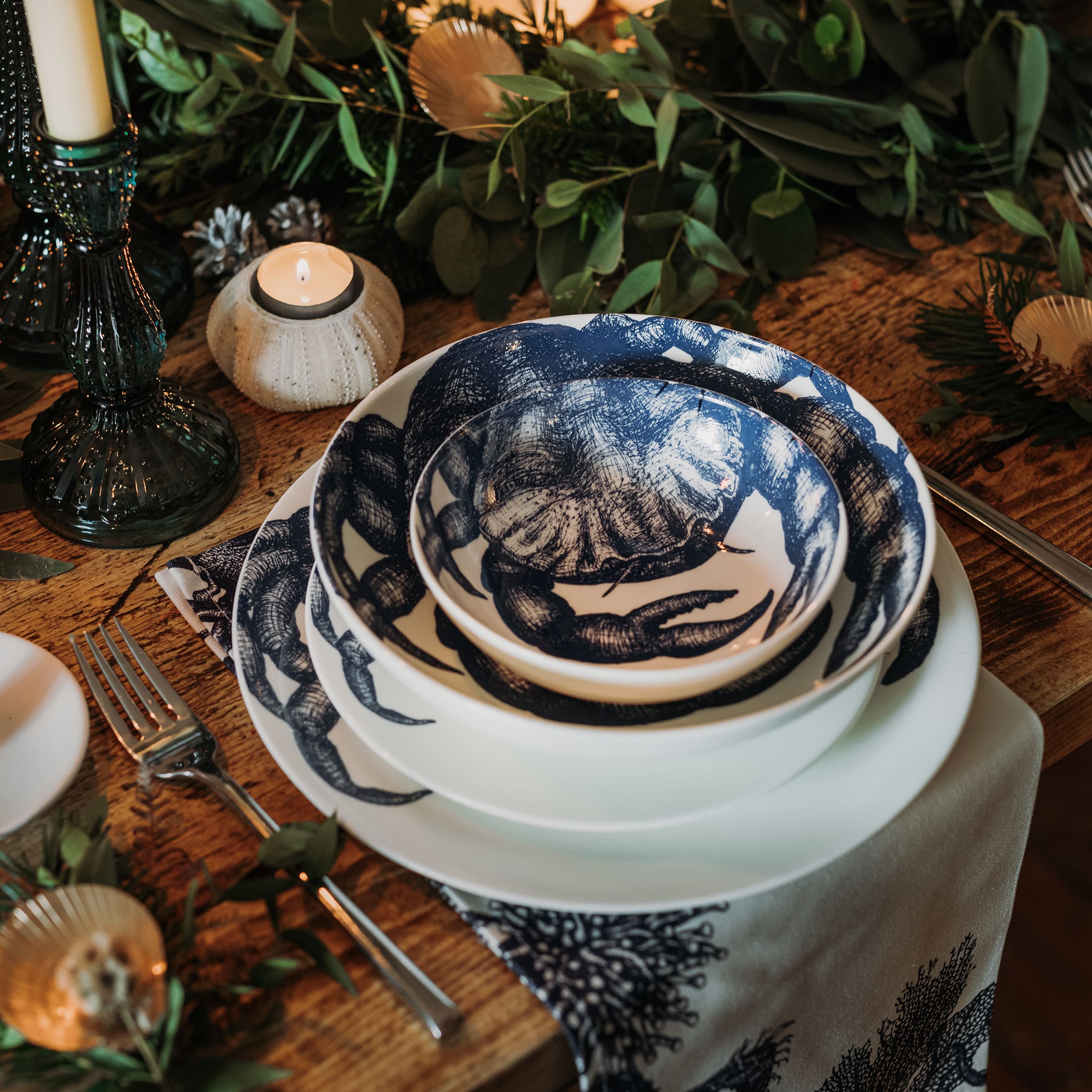 Pasta bowl in Bone China in our Classic range in Navy and white in the Crab design,placed on a Crab dinner plate and has a smaller bowl placed inside.All are on a table setting and the table is decorated with foliage and candle holders 