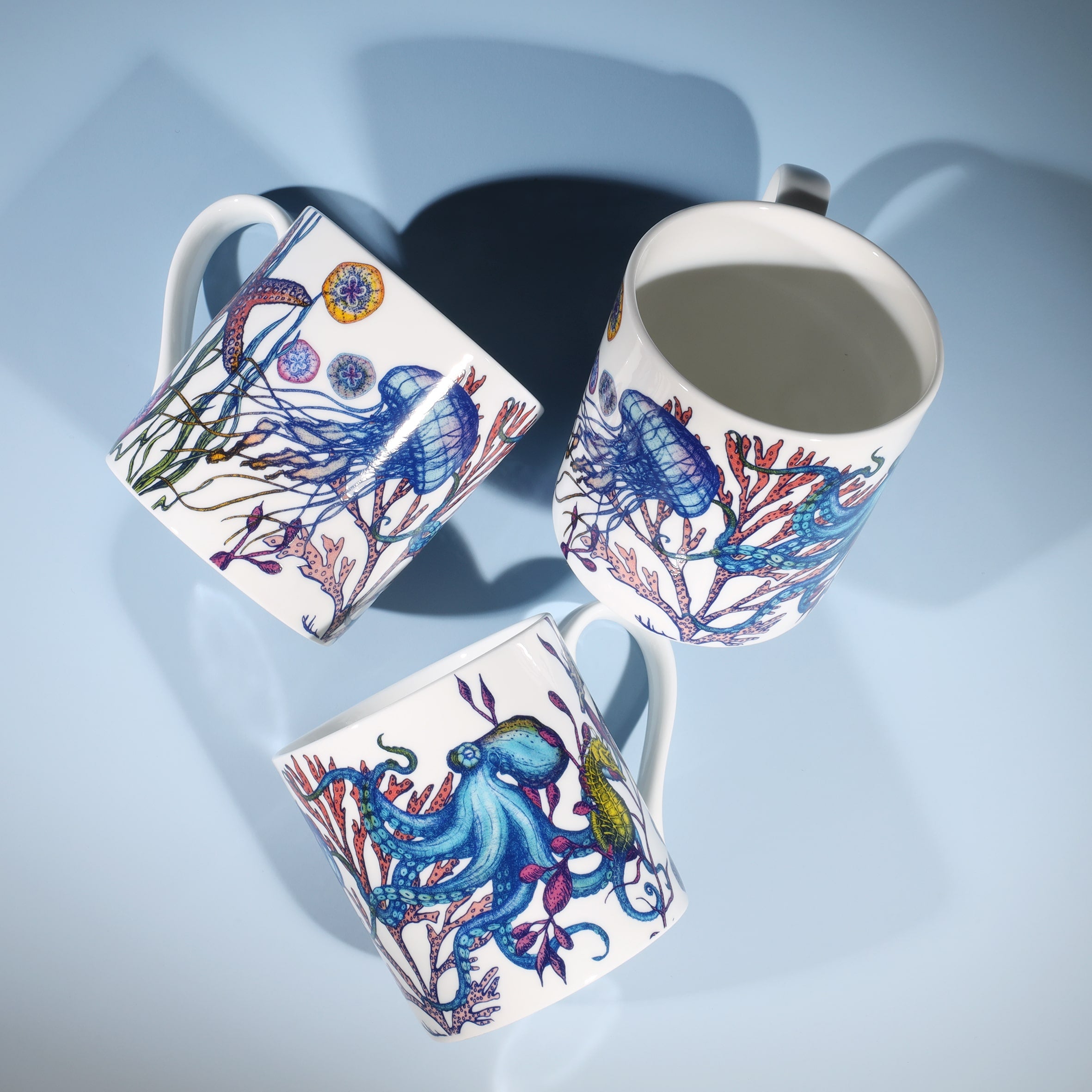 Shown from above is an Image of three bone china mugs featuring an underwater Reef Design with Octopus, Jellyfish and Starfish 