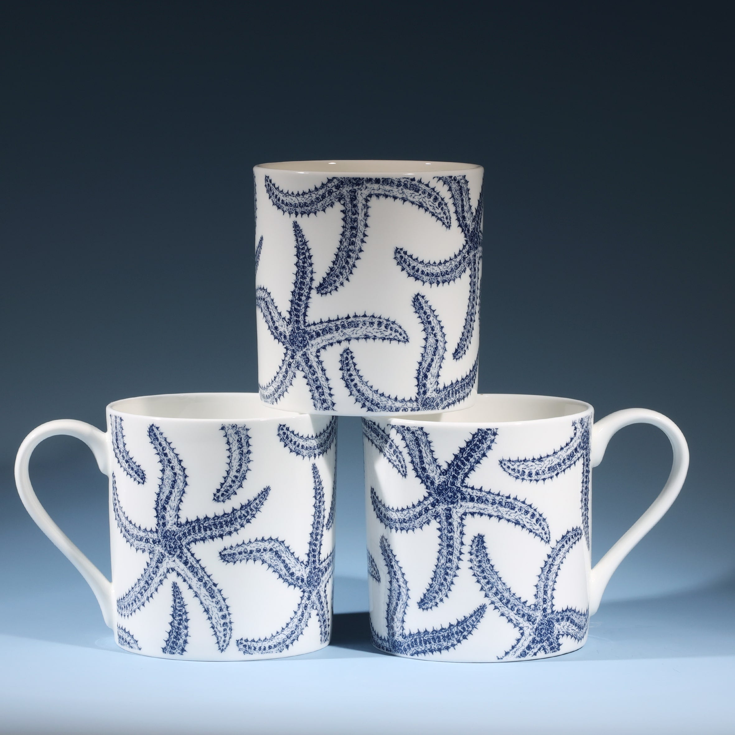 Bone china white mug featuring hand drawn Starfish design in classic navy in a stack of three